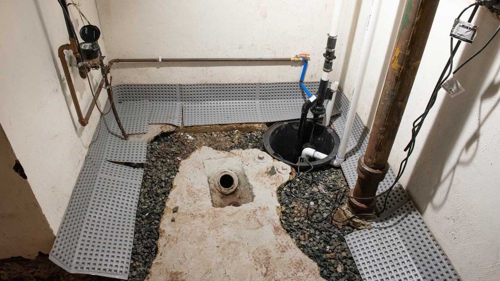 Basement sump pump being repaired by professionals at Dry Tech Waterproofing Solutions