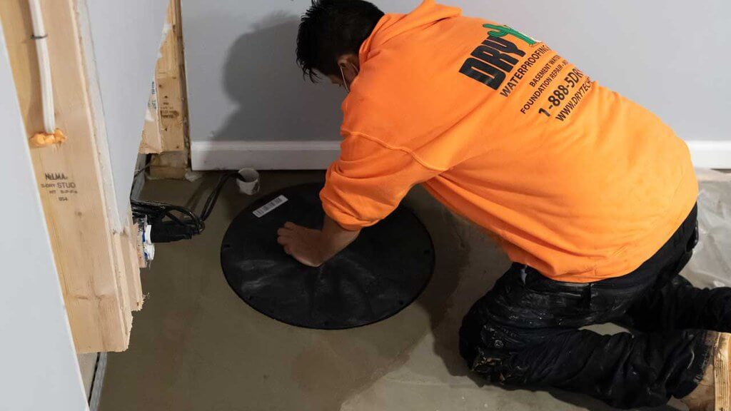 Technician working on covered sump pump in basement
