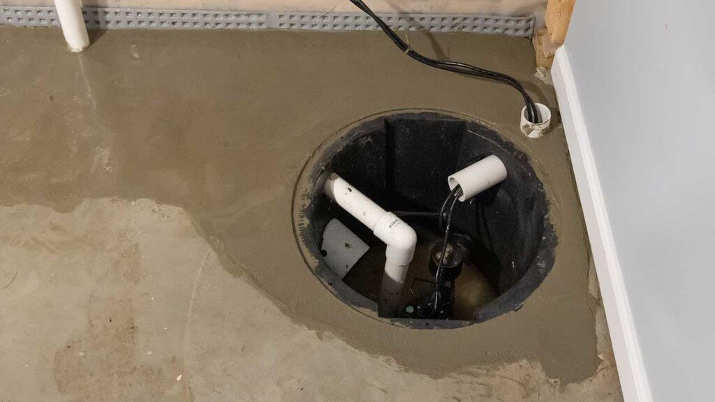 Open sump pump in corner of basement floor