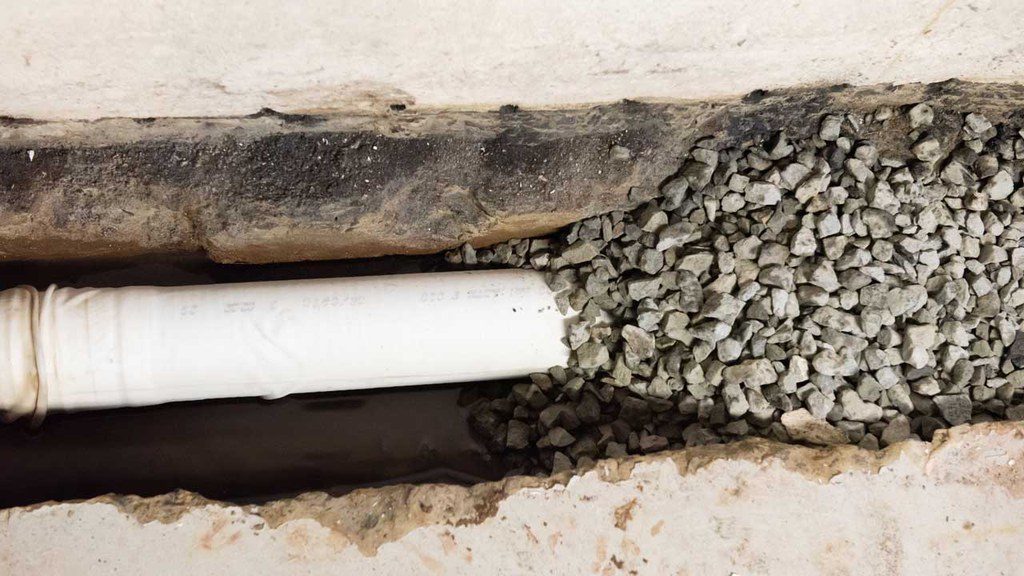 Drainage pipe in trench partially covered with stones