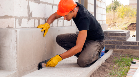 Worker spreading concrete along foundation line