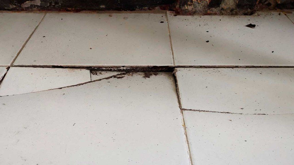 Broken tile sinking into the floor indicating foundational issue