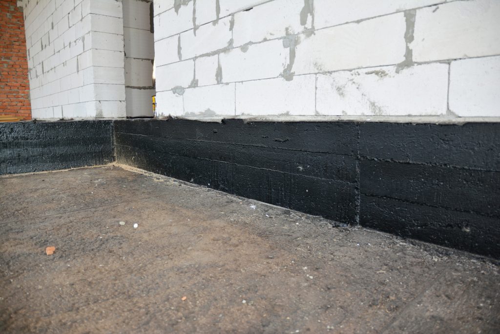Spray waterproofing applied to a basement foundation