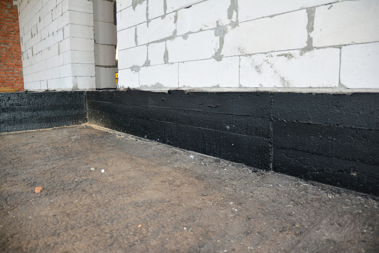 Spray waterproofing applied to a basement foundation