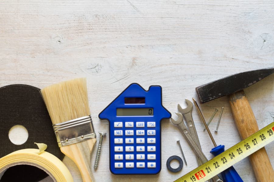 Blue calculator in shape of home next to tools needed for foundation crack repair