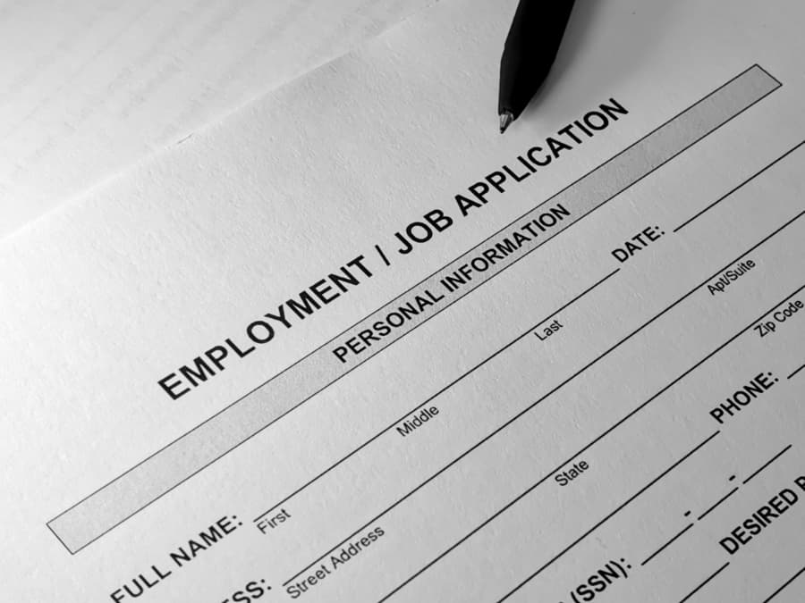 Job application form attached to clipboard with pen