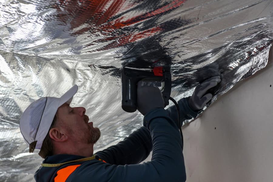 Worker in vest fixing vapor barrier